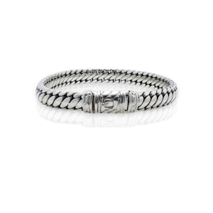 May include: A silver bracelet with a textured, woven design. The bracelet has a clasp closure.