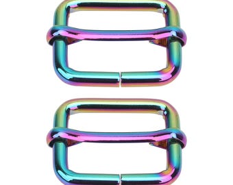 Op de afbeelding: Twee iriserende metalen rechthoekige schuifgespen. De gespen hebben een regenboogafwerking met tinten blauw, groen, paars en goud. De hardware is ontworpen voor gebruik bij het maken van tassen, naaien of andere knutselprojecten.
