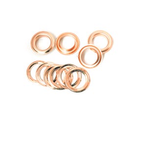 Könnte beinhalten: Ein Satz mit 10 goldfarbenen Metallstiften für Bastel- und DIY-Projekte. Die Ösen sind kreisförmig angeordnet, einige überlappen sich.