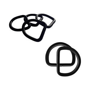 Op de afbeelding: Verschillende zwarte D-ringen in diverse vormen en maten zijn geplaatst tegen een witte achtergrond. Sommige zijn cirkelvormig, terwijl andere een meer hoekig, D-vormig ontwerp hebben. De ringen lijken gemaakt van een solide, matte materiaal.