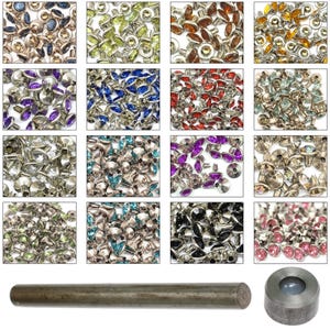 May include: Assortment of 16 colours of round, flat-back rhinestones with silver settings. The rhinestones are arranged in a grid pattern. There is also a silver tool for setting the rhinestones.