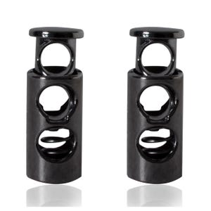 May include: Two black metal toggle cord locks with a spring mechanism. Each lock has three holes for threading cords.