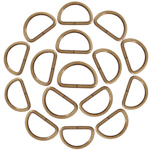 Peut inclure: Une collection d'anneaux en D de couleur laiton antique disposés en cercle. Chaque anneau en D est en forme de demi-cercle avec une ouverture articulée. La quincaillerie métallique est probablement utilisée pour l'artisanat, la fabrication de sacs ou d'autres projets de bricolage.