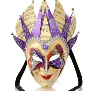 May include: A purple and gold Venetian masquerade mask with a jester's hat and a black ribbon. The mask has a smiling face with painted eyes and a red mouth.