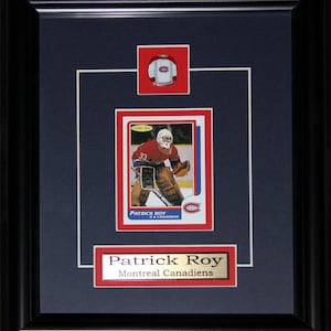 May include: Framed hockey card featuring Patrick Roy of the Montreal Canadiens. The card is set against a navy blue background with a red and white border. A small jersey illustration and a nameplate with "Patrick Roy" and "Montreal Canadiens" are also included.
