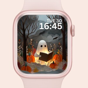 Puede incluir: Un reloj inteligente de oro rosa muestra una imagen de Halloween. La esfera del reloj muestra un fantasma blanco leyendo un libro en un bosque con calabazas y murciélagos. La hora es 16:45 el martes 30.