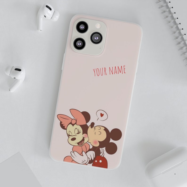 Op de afbeelding: Roze telefoonhoes met een cartoon afbeelding van Mickey Mouse en Minnie Mouse die elkaar kussen. De hoes heeft ruimte voor een gepersonaliseerde naam, "YOUR NAME".