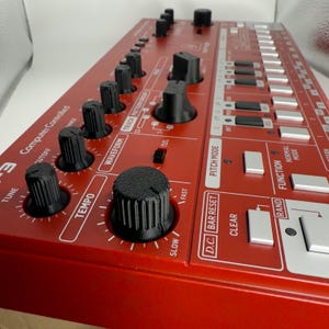 May include: A red synthesizer with black knobs and buttons. The synthesizer has labels for "Tune", "Tempo", "Waveform", "Track Pattern", "D.C. Bar Reset", "Pitch Mode", "Clear", "Rand", "Function", and "Normal Mode".