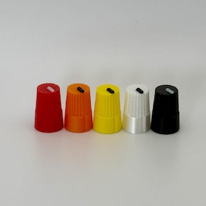 May include: Five cylindrical control knobs arranged in a row, featuring vertical ridges along the sides. The knobs are colored red, orange, yellow, white, and black, each topped with a small, contrasting indicator line on the flat circular surface.