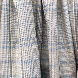May include: Close-up of four fabric swatches with a blue and white plaid pattern. The fabric is woven with a subtle texture.