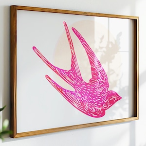 May include: A framed print featuring a stylized pink swallow with intricate patterns. The artwork is set against a white background with a soft, circular shape behind the bird. The frame is made of light brown wood.