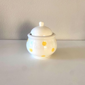 May include: White ceramic sugar bowl with a lid, decorated with yellow polka dots.
