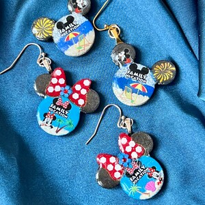 May include: Four pairs of Mickey Mouse and Minnie Mouse themed earrings. The earrings feature a beach scene with the words "Family Vacation". The Minnie Mouse earrings have red and white polka dot bows. The earrings have gold and silver hooks.