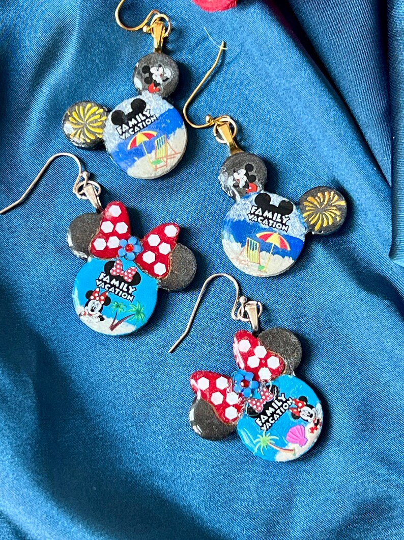 May include: Four pairs of Mickey Mouse and Minnie Mouse themed earrings. The earrings feature a beach scene with the words "Family Vacation". The Minnie Mouse earrings have red and white polka dot bows. The earrings have gold and silver hooks.