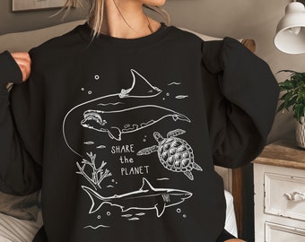 May include: Black sweatshirt with a white graphic design of a whale, shark, turtle, and coral reef. The text "SHARE the PLANET" is printed on the sweatshirt.