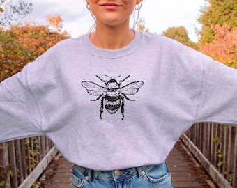 May include: A gray sweatshirt with a black and white bee graphic on the front.