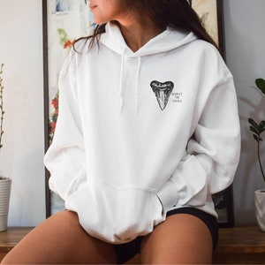 May include: White hoodie with a black shark tooth graphic and the text "Respect the Locals" printed on the front.