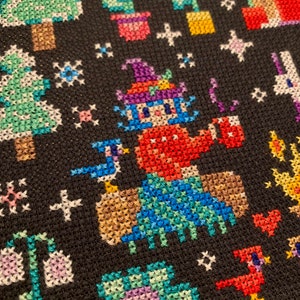 May include: A colorful cross-stitch pattern featuring a whimsical character wearing a hat and holding a cup, surrounded by trees, flowers, and other small details.