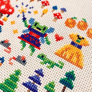May include: Cross-stitch embroidery featuring a green and blue fairy with a red dress, a yellow dog with a blue collar, and pumpkins. The background includes trees, mushrooms, and stars.