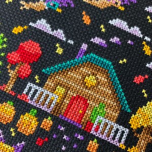 May include: A cross-stitch design featuring a whimsical Halloween scene. A brown house with a teal roof and red door is surrounded by pumpkins, trees, and flying witches against a black background. The design uses various colors to create a festive atmosphere.