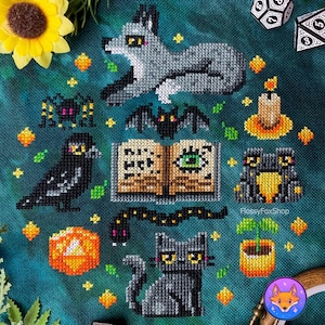 Könnte beinhalten: Kreuzstich-Design mit einem grauen Wolf, einer schwarzen Katze, einem Raben, einer Spinne und einer Fledermaus. Das Design umfasst ein Buch mit einem Auge, eine Kerze, einen Kürbis und eine Schlange. Der Hintergrund ist türkis mit gelben und orangefarbenen Akzenten.