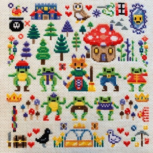 K&ouml;nnte beinhalten: Kreuzstich-Stickmuster mit einer fantasievollen Waldszene mit einem Fuchs, Pilzen, Fr&ouml;schen und einem Vogelhaus. Das Design ist auf wei&szlig;em Aida-Stoff mit buntem Garn gestickt.