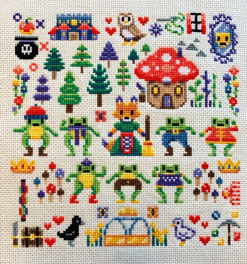 K&ouml;nnte beinhalten: Kreuzstich-Stickmuster mit einer fantasievollen Waldszene mit einem Fuchs, Pilzen, Fr&ouml;schen und einem Vogelhaus. Das Design ist auf wei&szlig;em Aida-Stoff mit buntem Garn gestickt.