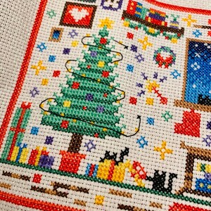 Puede incluir: Patr&oacute;n de punto de cruz que representa una escena navide&ntilde;a con un &aacute;rbol verde, regalos y una casa con una ventana. El &aacute;rbol est&aacute; decorado con luces y adornos. Los regalos est&aacute;n envueltos en papel rojo, verde y azul. La casa tiene un techo blanco y una ventana azul.