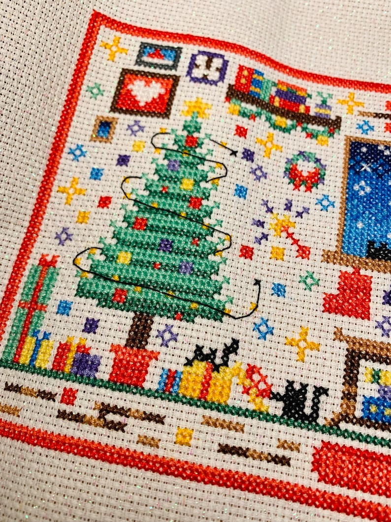 Puede incluir: Patr&oacute;n de punto de cruz que representa una escena navide&ntilde;a con un &aacute;rbol verde, regalos y una casa con una ventana. El &aacute;rbol est&aacute; decorado con luces y adornos. Los regalos est&aacute;n envueltos en papel rojo, verde y azul. La casa tiene un techo blanco y una ventana azul.