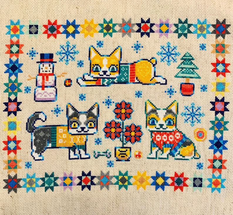 Peut inclure: Motif de point de croix repr&eacute;sentant quatre chats portant des pulls et un bonhomme de neige. L'arri&egrave;re-plan est une bordure color&eacute;e d'&eacute;toiles et de flocons de neige.