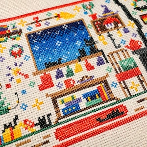 Puede incluir: Patr&oacute;n de punto de cruz de una habitaci&oacute;n con una ventana que muestra un cielo nocturno estrellado, una estanter&iacute;a con libros y un gato sentado en un alf&eacute;izar de la ventana. La habitaci&oacute;n est&aacute; decorada con una corona, una escoba y un sombrero de bruja.