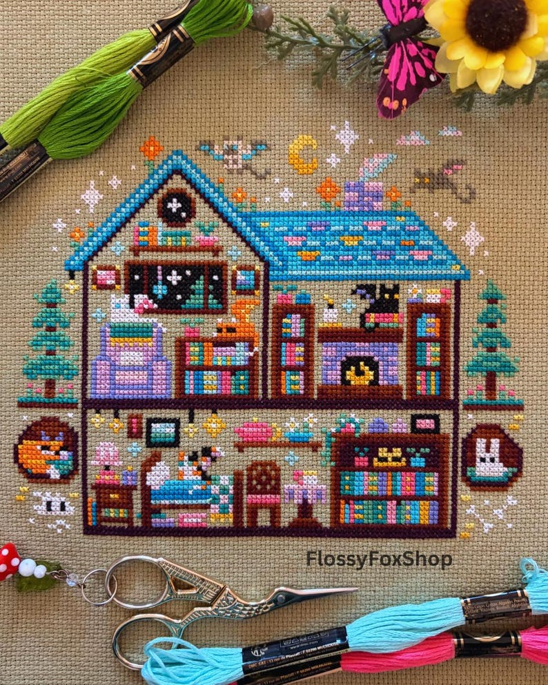 May include: A cross-stitch pattern of a whimsical two-story house with a blue roof and colorful details. The design includes bookshelves, a fireplace, and various decorative elements. The text "FlossyFoxShop" is visible.