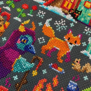 May include: A colorful cross-stitch pattern featuring a fox, a bird, a campfire, and a house. The pattern is on a dark gray background.