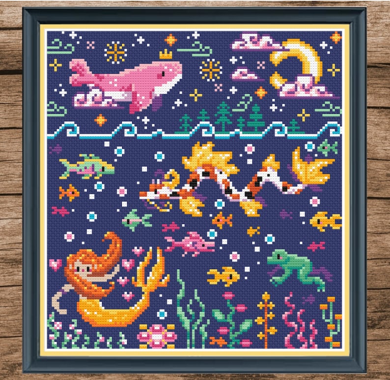 May include: A cross-stitch pattern featuring a mermaid, a pink whale, and a koi fish swimming in a blue ocean with a moon and stars in the sky. The pattern is surrounded by a dark blue frame.