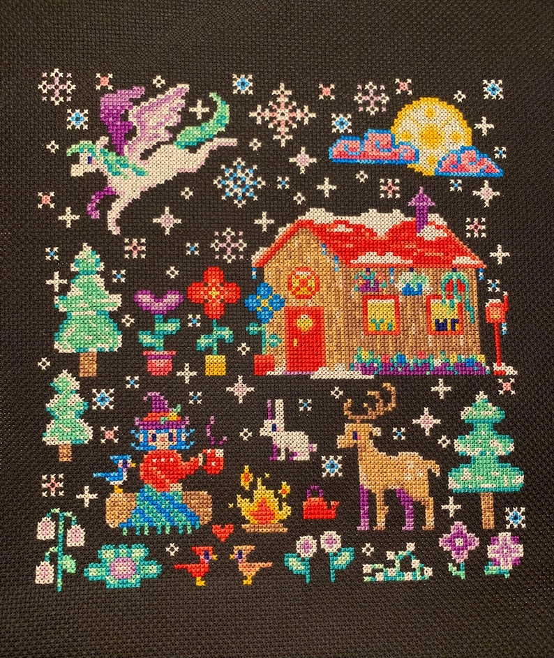 May include: A cross-stitch pattern depicting a winter scene with a small house, a flying unicorn, a deer, a rabbit, a witch, and a campfire. The scene is set against a dark blue background with white snowflakes.
