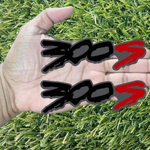 May include: Two black and red ant stickers on a hand. The ants are stylized and have a cartoonish look.