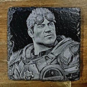 Puede incluir: Una imagen grabada en blanco y negro de un personaje de videojuego que lleva un casco y gafas protectoras. El personaje está representado en una postura de combate con un arma.