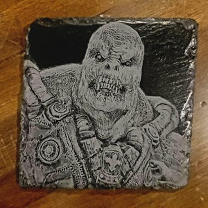 Puede incluir: Una imagen grabada en blanco y negro de una criatura monstruosa con dientes afilados y una expresión amenazante. La criatura lleva una armadura detallada y texturizada.