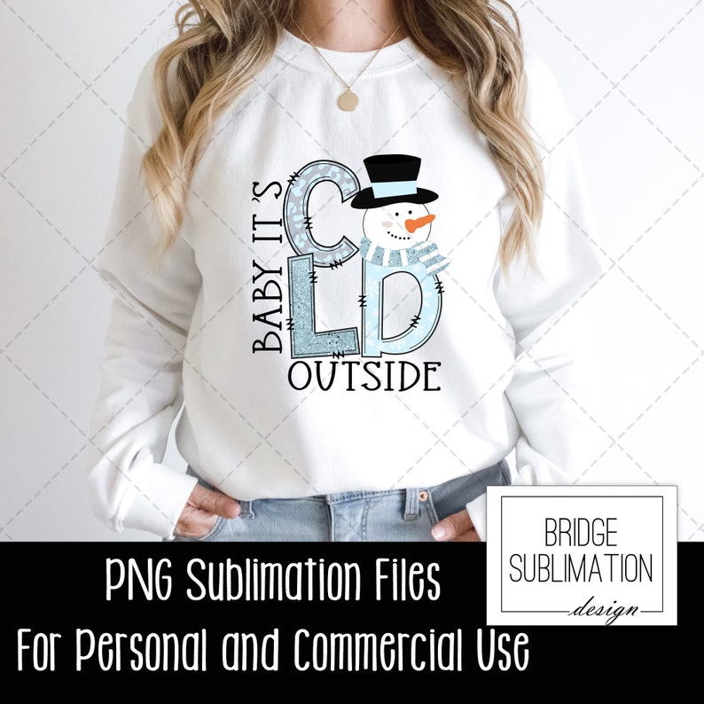 May include: A white sweatshirt with a blue and gray graphic design that says "Baby It's Cold Outside" with a snowman illustration. The design is perfect for winter.