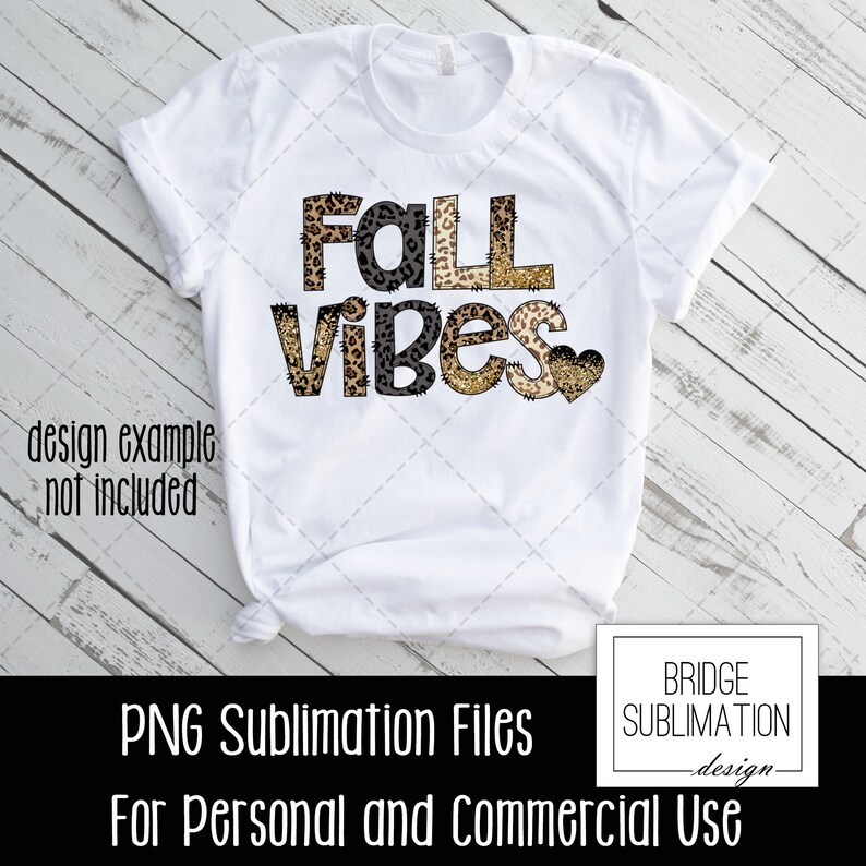 May include: White t-shirt with the text "Fall Vibes" in black letters with a leopard print design. The text is layered with a gold glitter effect. A small heart with a leopard print design is to the right of the text.