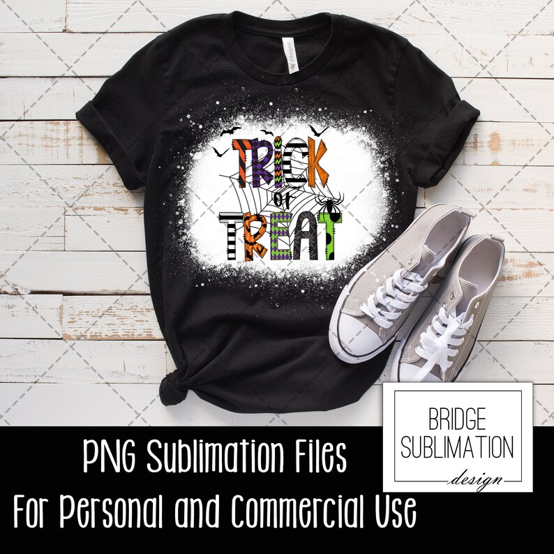 May include: Black t-shirt with a white splatter design and the words "Trick or Treat" in colorful patterned letters. The letters are decorated with spiderwebs, bats, and spiders.