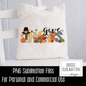 May include: A cream-colored tote bag with the words "give thanks" in a colorful, fall-themed design. The design includes a pilgrim hat, pumpkin, turkey, and autumn leaves. The bag is sitting on a white chair.