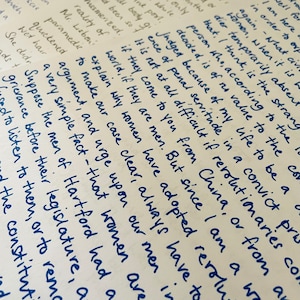 Puede incluir: Un primer plano de notas escritas a mano en papel de color crema. Las notas est&aacute;n escritas con tinta azul y tratan el tema de los derechos de las mujeres y las revoluciones. El texto incluye frases como "las mujeres son humanas", "los revolucionarios vienen de China" y "no es nada dif&iacute;cil si vienen de China".