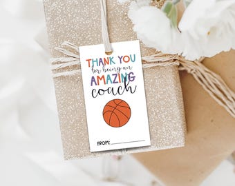 May include: A white gift tag with colourful text that reads "Thank you for being an amazing coach". A basketball is illustrated in the centre of the tag. The tag has a blank line for a name at the bottom.