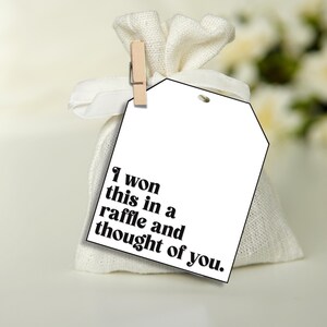 Puede incluir: Una bolsa de regalo blanca con una etiqueta blanca que dice "Gan&eacute; esto en una rifa y pens&eacute; en ti."