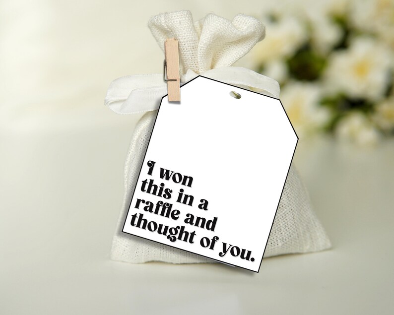 Puede incluir: Una bolsa de regalo blanca con una etiqueta blanca que dice "Gan&eacute; esto en una rifa y pens&eacute; en ti."