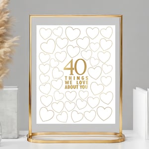 Op de afbeelding: Een gouden lijst met een witte achtergrond en 40 gouden harten. De tekst "40 dingen die we van je houden" staat in gouden letters.