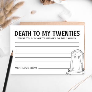 May include: A white card with the text "DEATH TO MY TWENTIES" and lines for writing. A tombstone illustration is on the right. A pencil and dried flowers are in the background. The card is inside a brown envelope.