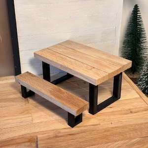 Peut inclure: Une table de pique-nique miniature en bois avec un cadre en m&eacute;tal noir. La table a une finition en bois naturel et mesure environ 38 cm de long.
