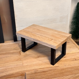 Peut inclure: Un petit banc en bois avec des pieds en m&eacute;tal noir. Le banc est en bois clair et a une finition naturelle. Les pieds sont carr&eacute;s et ont une finition noire en poudre.